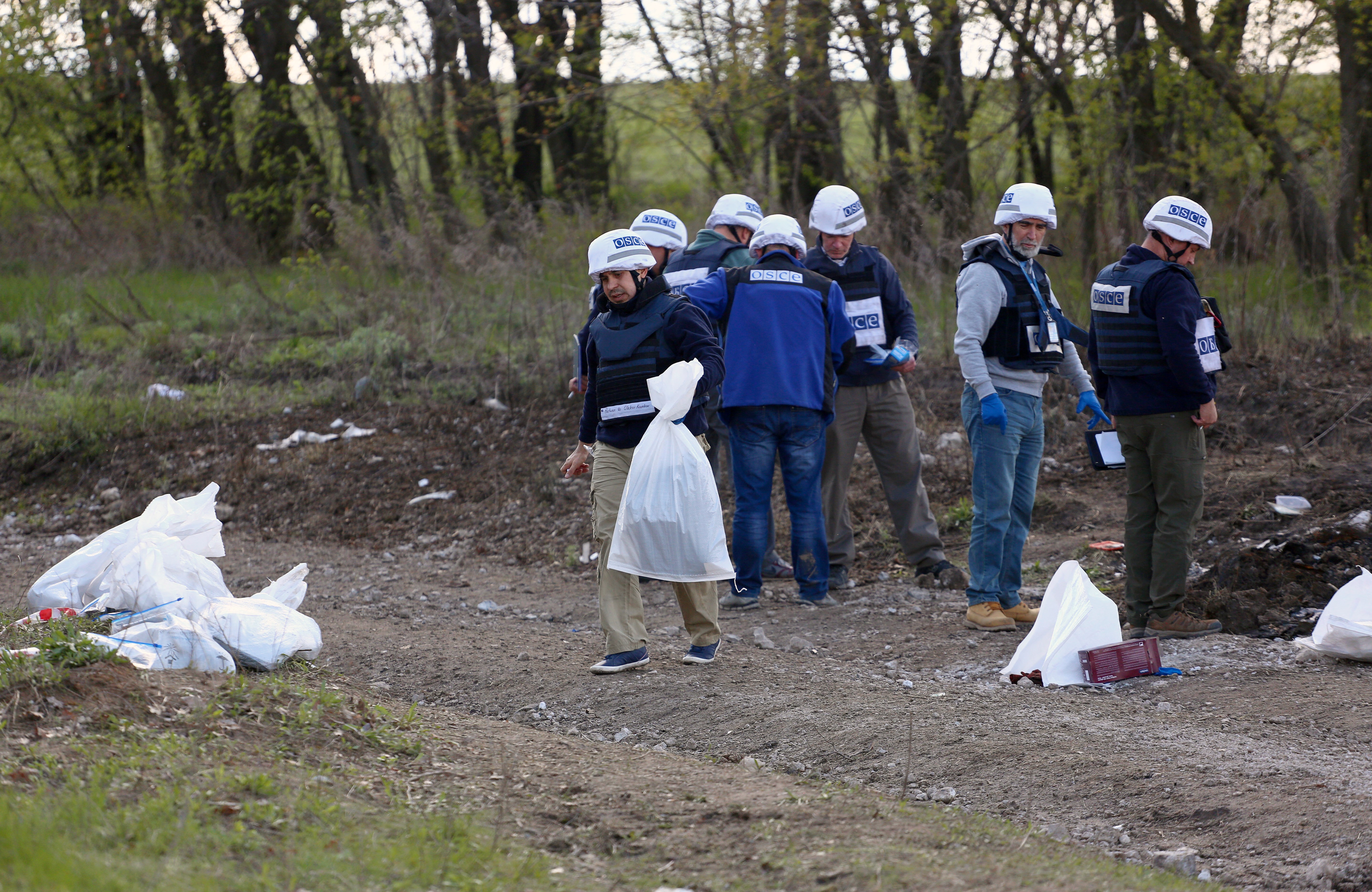 OSZE-Mitarbeitende sammeln Beweisstücke in einem Wald