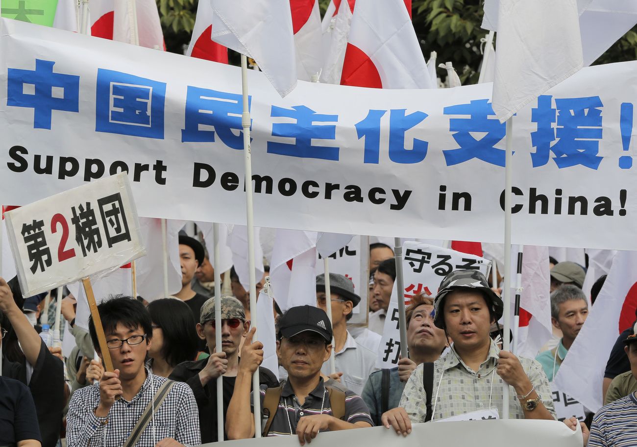 「中国民主化支援」と書かれた横断幕を持って行進する人々