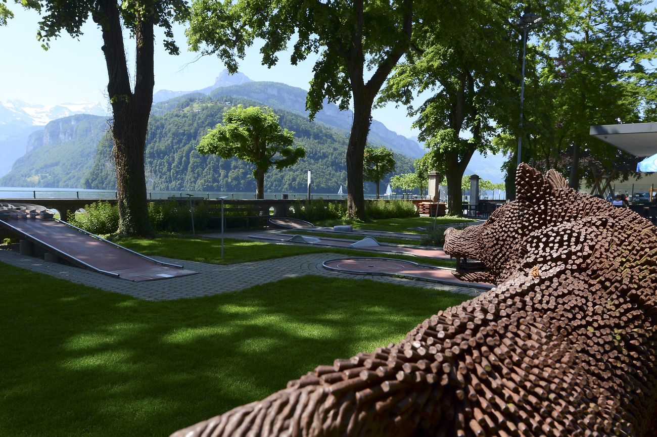 Einige von Bäumen beschattete Minigolfbahnen, im Hintergrund ein See
