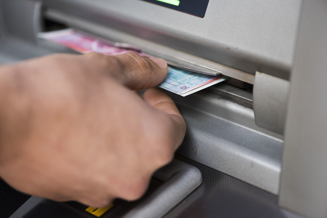 Main tirant des billet des 20 francs d'un Bancomat