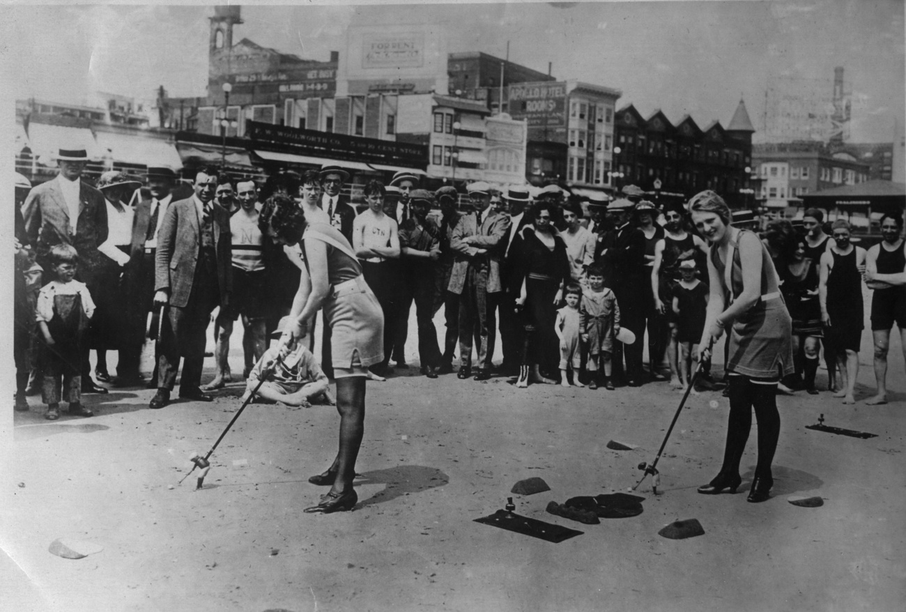 Zwei Frauen spielen 1925 an einem Strand im Badekostüm eine Art von Minigolf