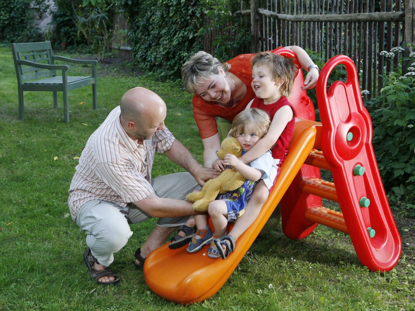 famiglia con bimbi piccoli su scivolo di plastica