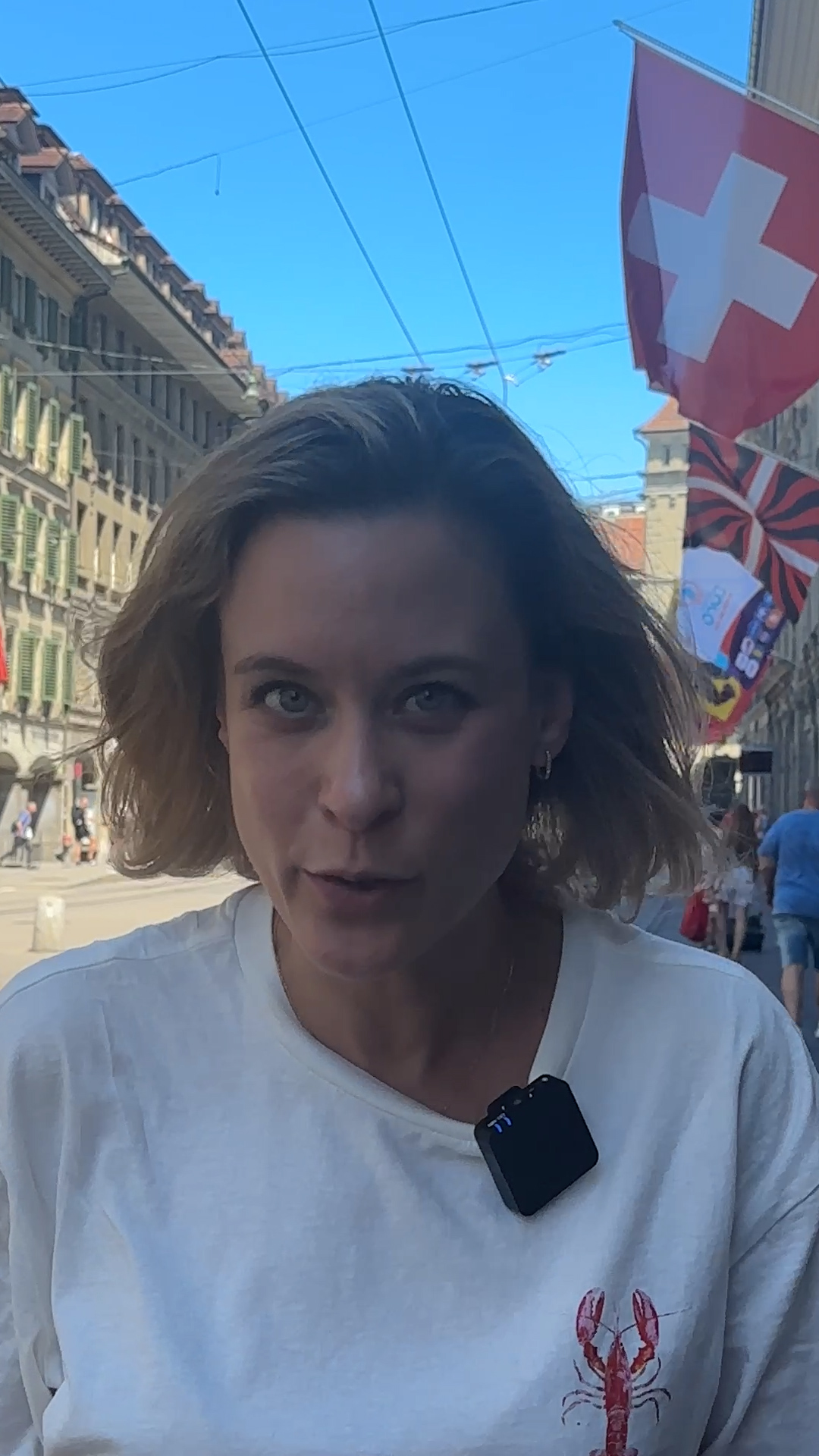 Photo of a young woman in a street with Swiss flag in the background.
