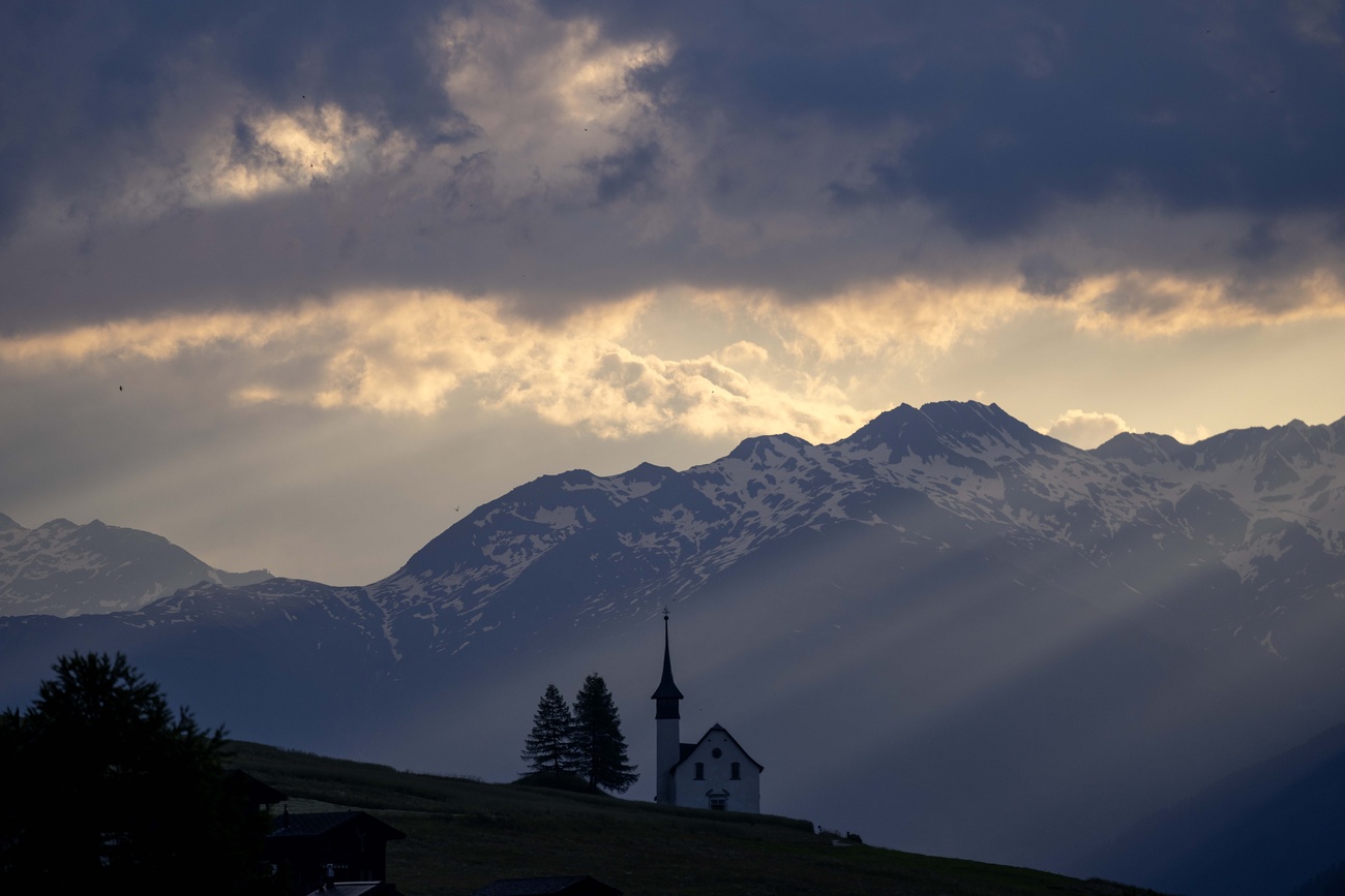 The sun rises behind a chapel early morning in Ritzingen near Goms, Switzerland