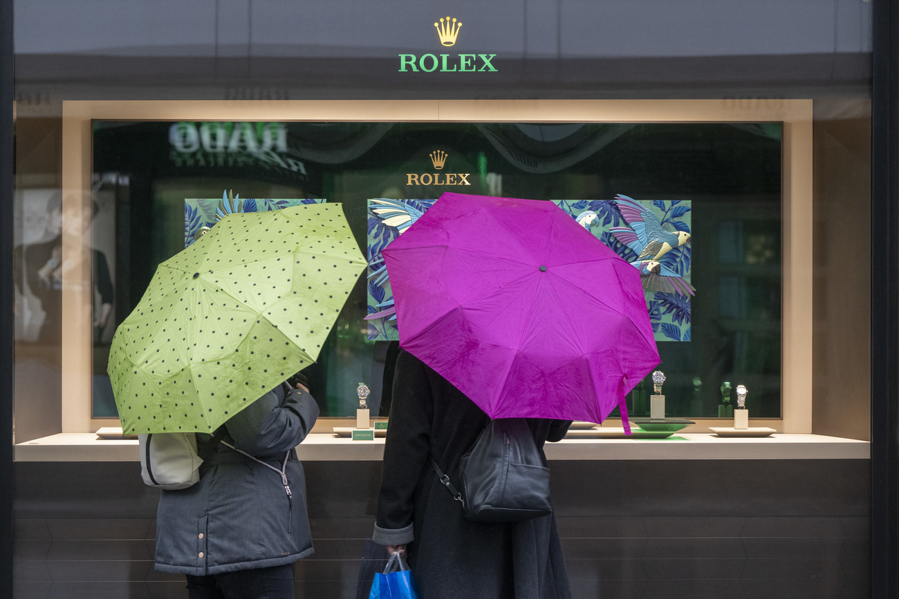 people with umbrellas in front of rolex shop