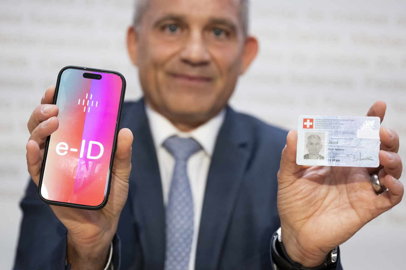 un uomo mostra una carta d'identità di plastica e uno smartphone sul cui schermo c'è scritto e-id