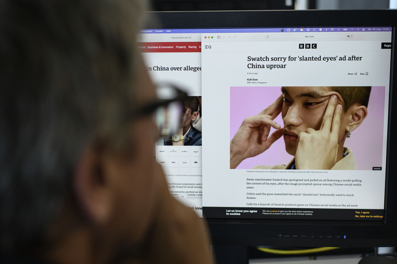 Ein Mann schaut auf einen Computerbildschirm, darauf der Artikel der BBC und das Bild mit den zum Schlitz gezogenen Augen.