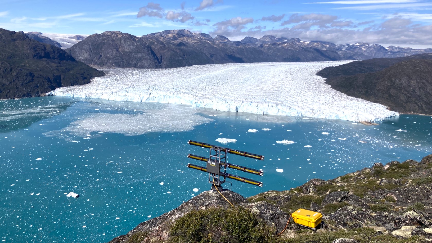 Blick auf einen Gletscher in einem Fjord, im Vordergrund ein Radargerät