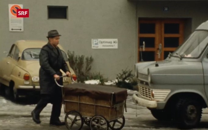 Zeitungsverteiler schiebt Wagen vor sich her