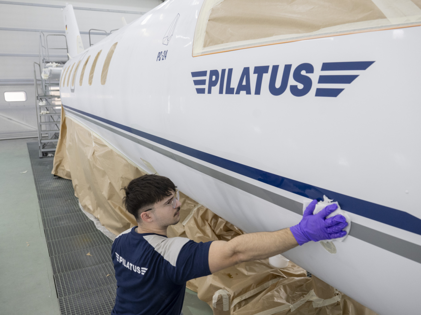 operaio pulisce parete esterna aereo pilatus