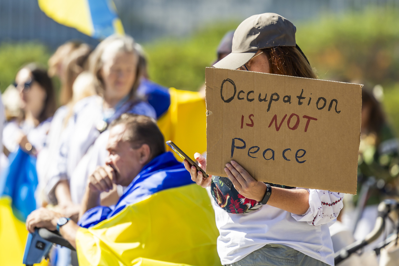 Женщина держит плакат с надписью «Оккупация — это не мир» во время акции в честь Дня независимости Украины на площади Наций перед штаб-квартирой ООН в Женеве, Швейцария, в воскресенье, 24 августа 2025 года.