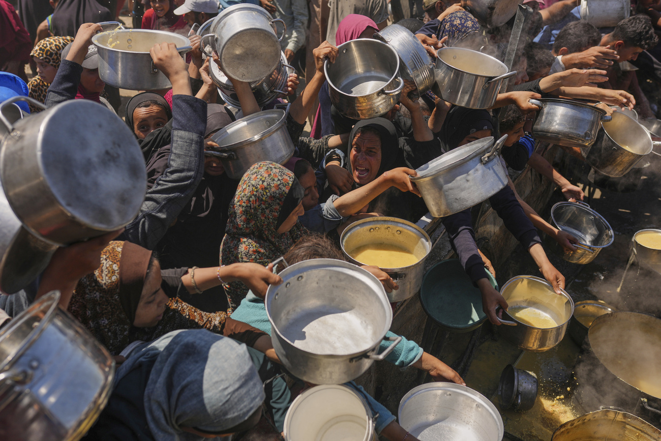 Palestinians struggle to get donated food at a community kitchen in Gaza City, northern Gaza Strip, Monday, Aug. 4, 2025.