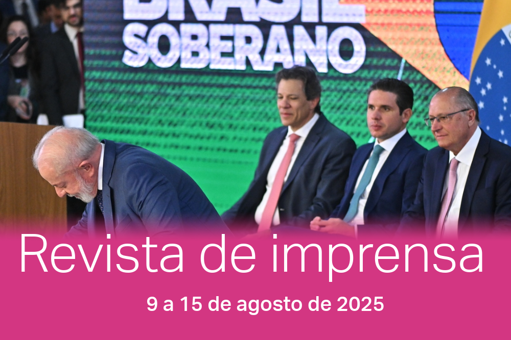 Três homens sentados e um curvado, assinando um papel