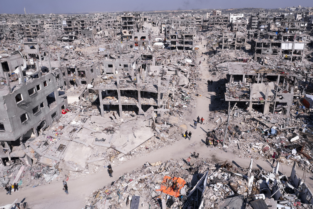 An aerial photograph taken by a drone shows Palestinians walking through the destruction caused by the Israeli air and ground offensive in Jabaliya, Gaza Strip, Wednesday, Jan. 29, 2025. (AP Photo/Mohammad Abu Samra)