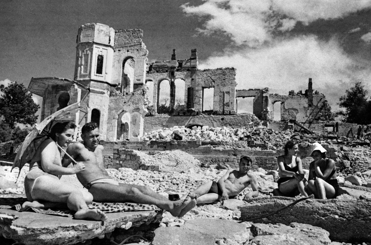 Menschen vor Ruinen am Sonnenbaden