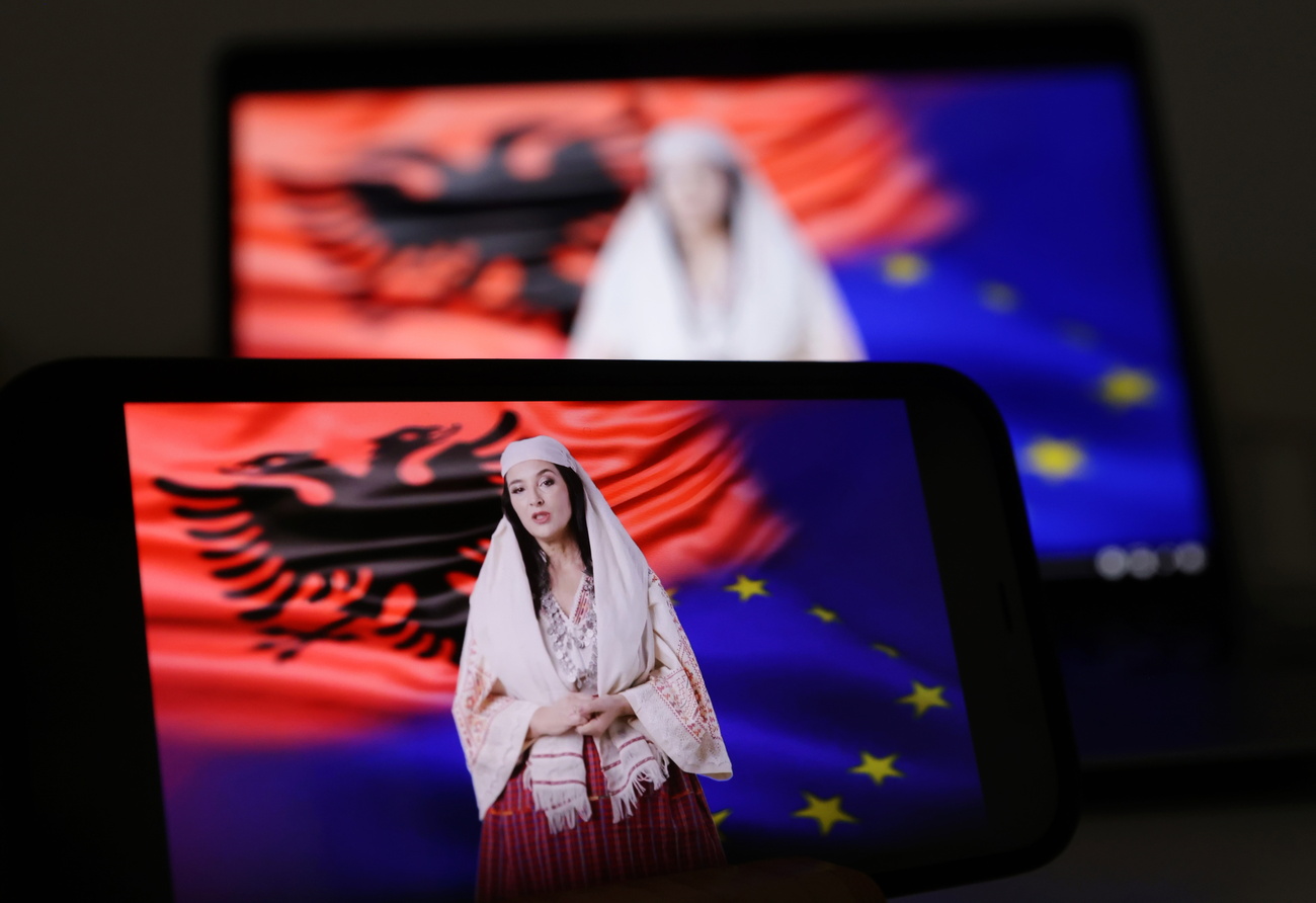 la ministra viruale albanese diella in abiti tradizionali. dietro di lei una bandiera albanese e una dell'UE