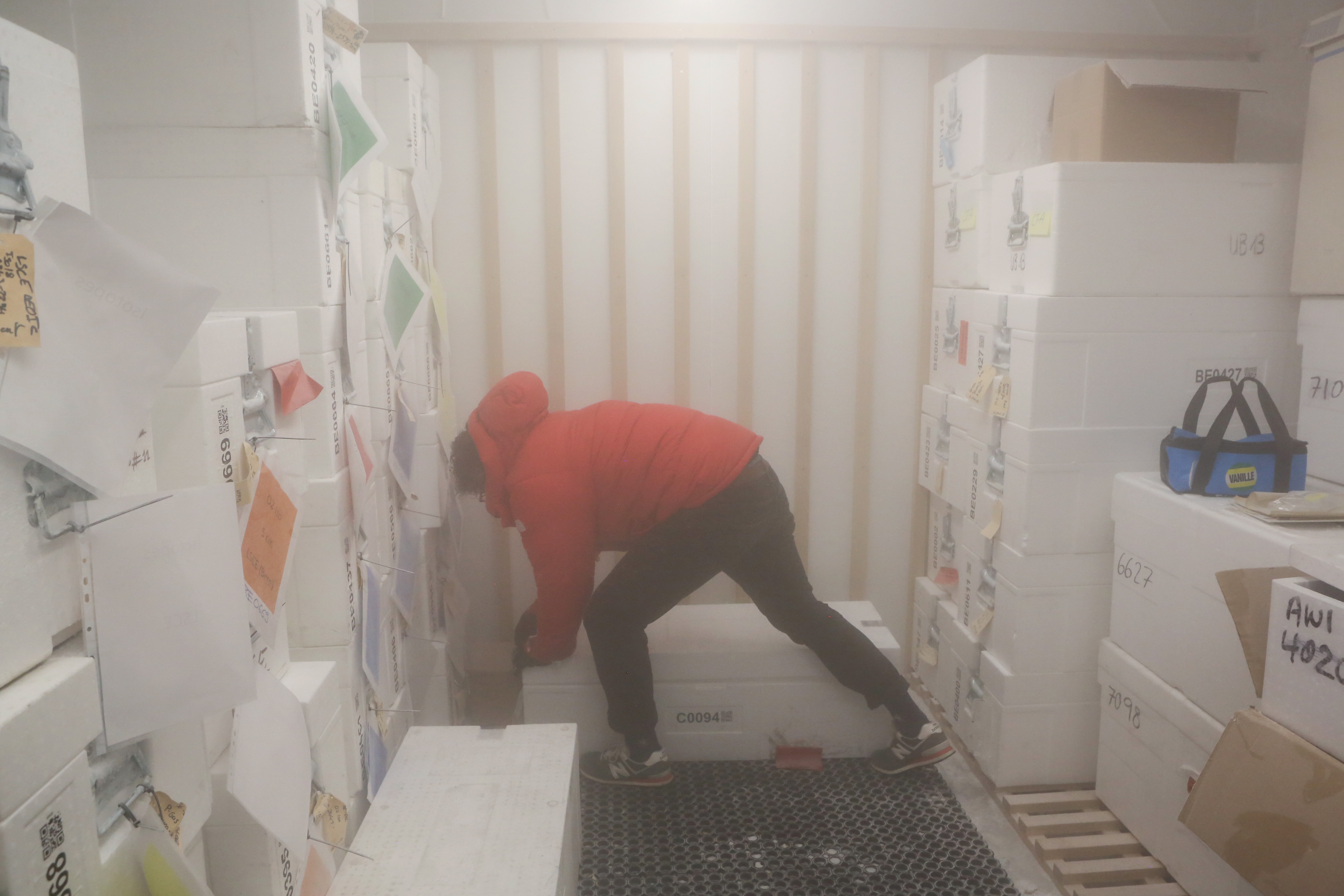 Mann in roter Jacke bückt sich über Styroporbox.