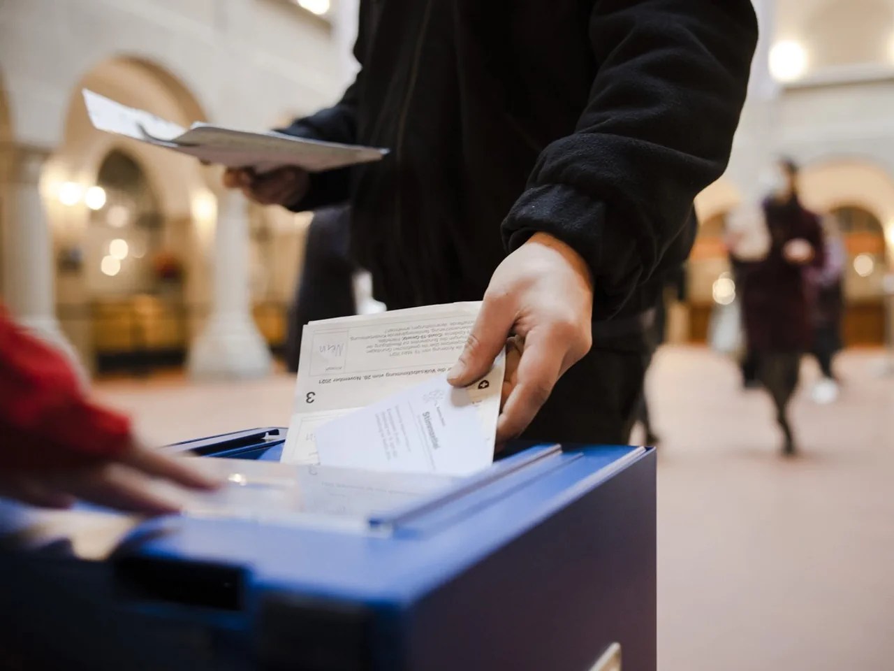 un homme dépose un bulletin de vote dans une urne