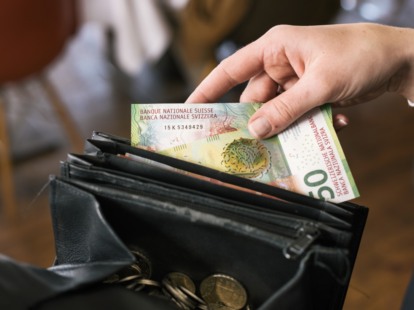 cameriera inserisce due biglietti da 50 franchi nel portamonete del lavoro