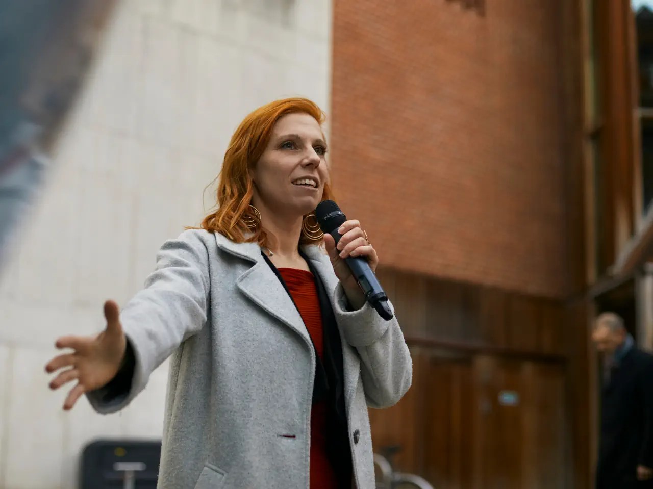 Frau ingrauem Mantel mit Mikrofon