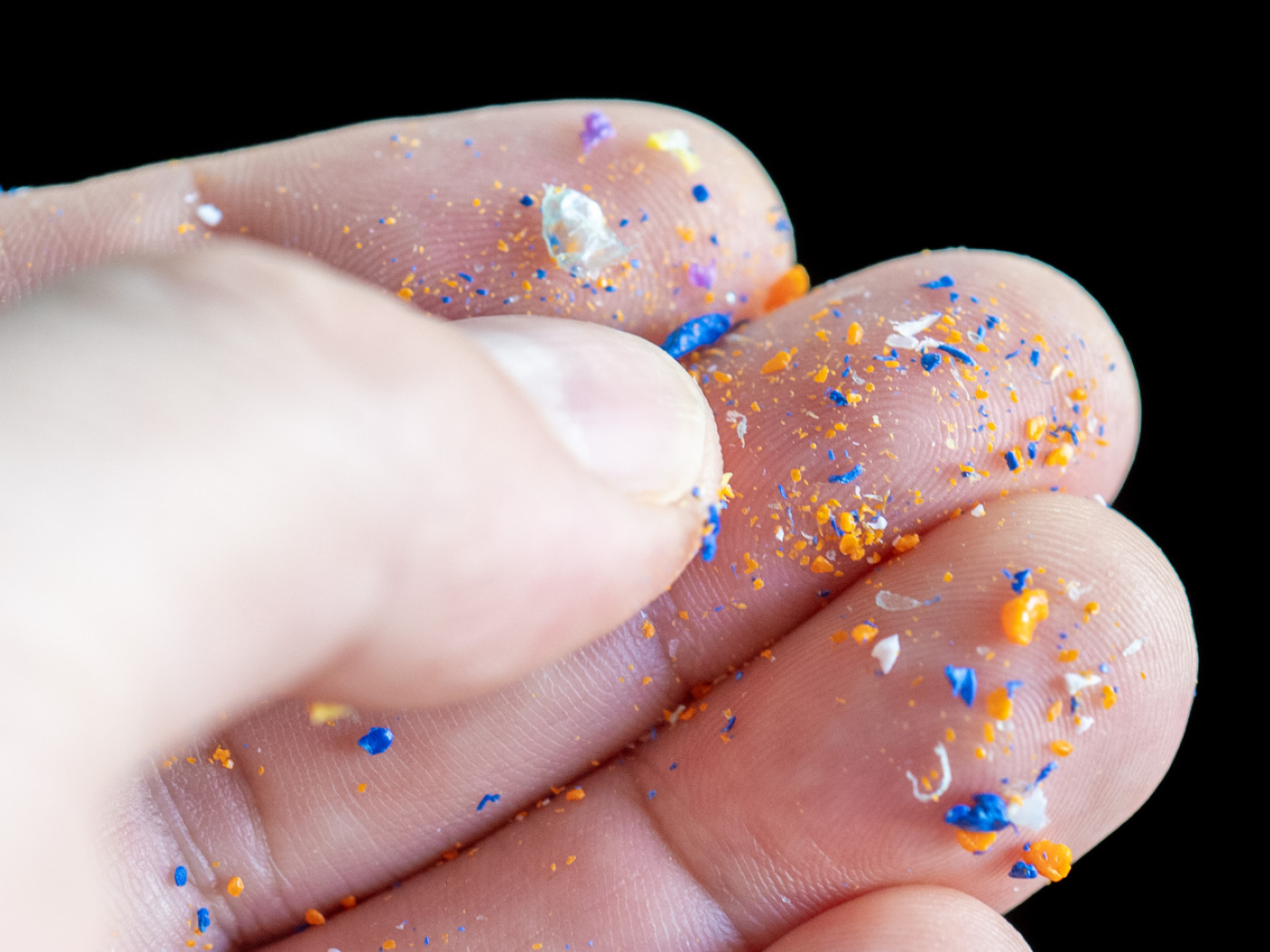 primo piano di dita di una mano coperte di microplastiche