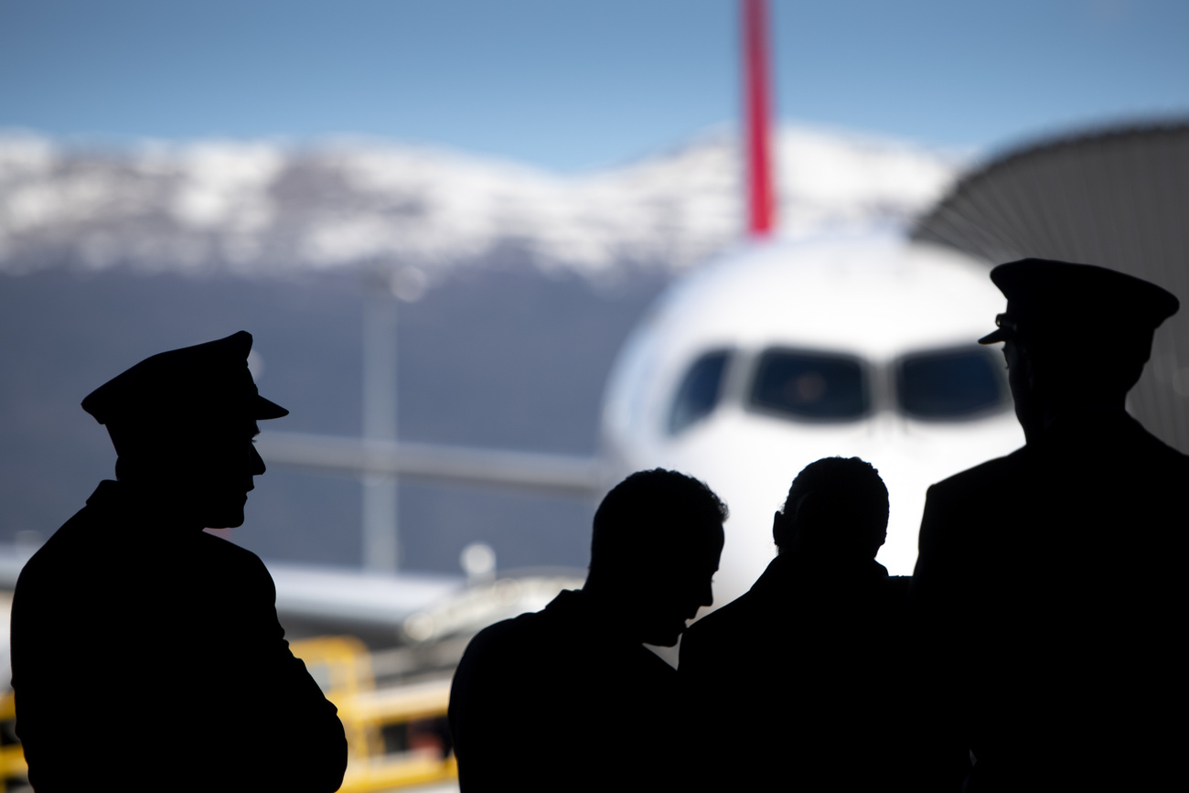 Un aereo sullo sfondo e sagome in scuro dell'equipaggio in primo piano