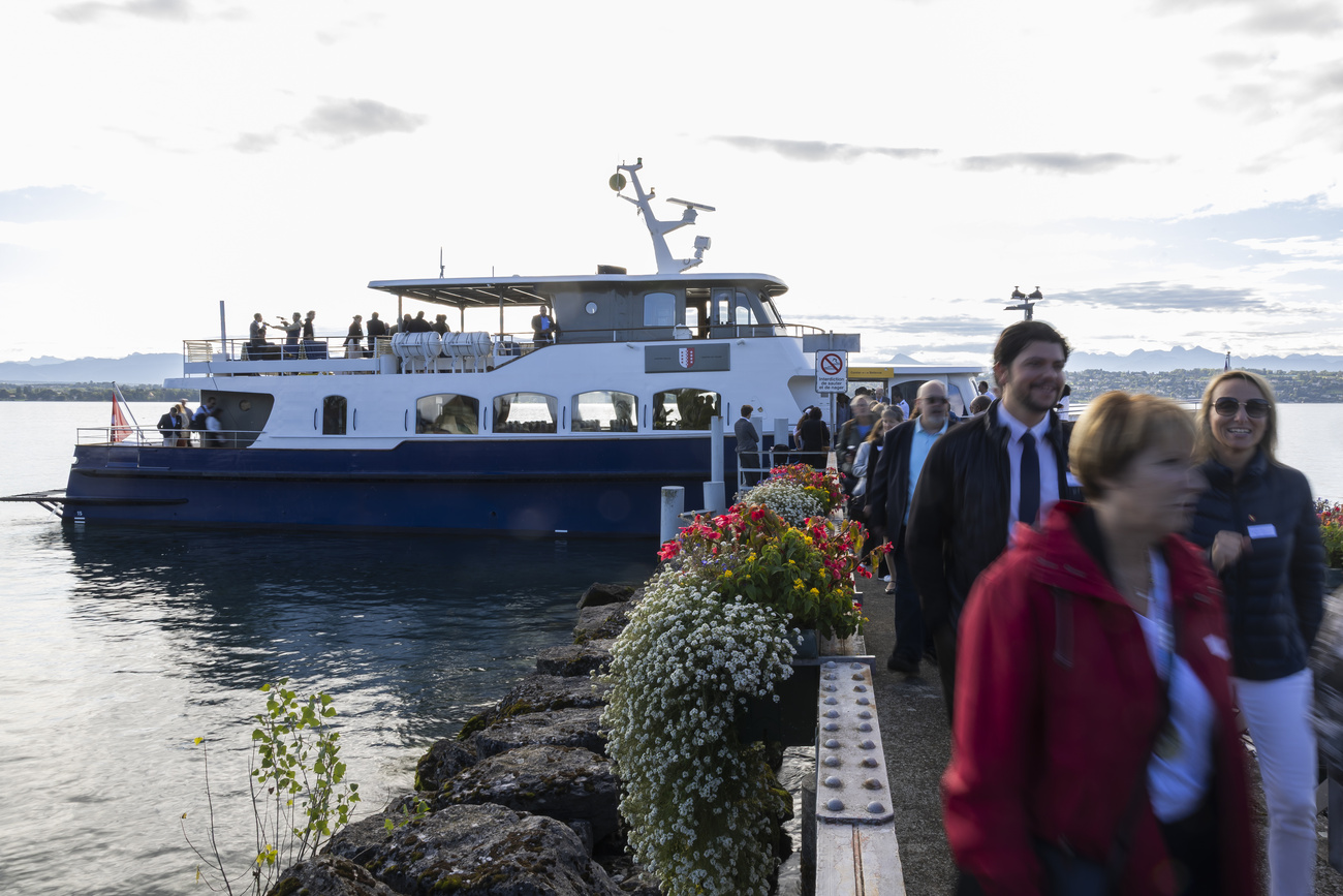 Photo of people on a dock and a boat on a lake in the background