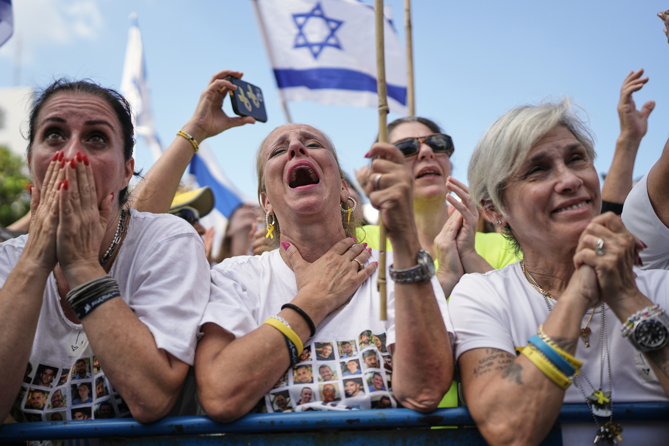 La gente reagisce mentre si raduna per assistere alla trasmissione in diretta del rilascio degli ostaggi israeliani da Gaza