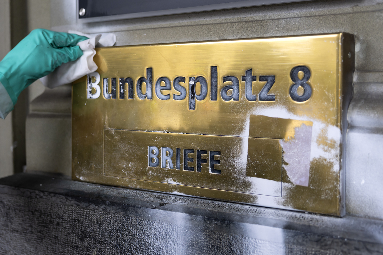eine Hand putzt das Messingschild für die Adresse "Bundesplatz 8)