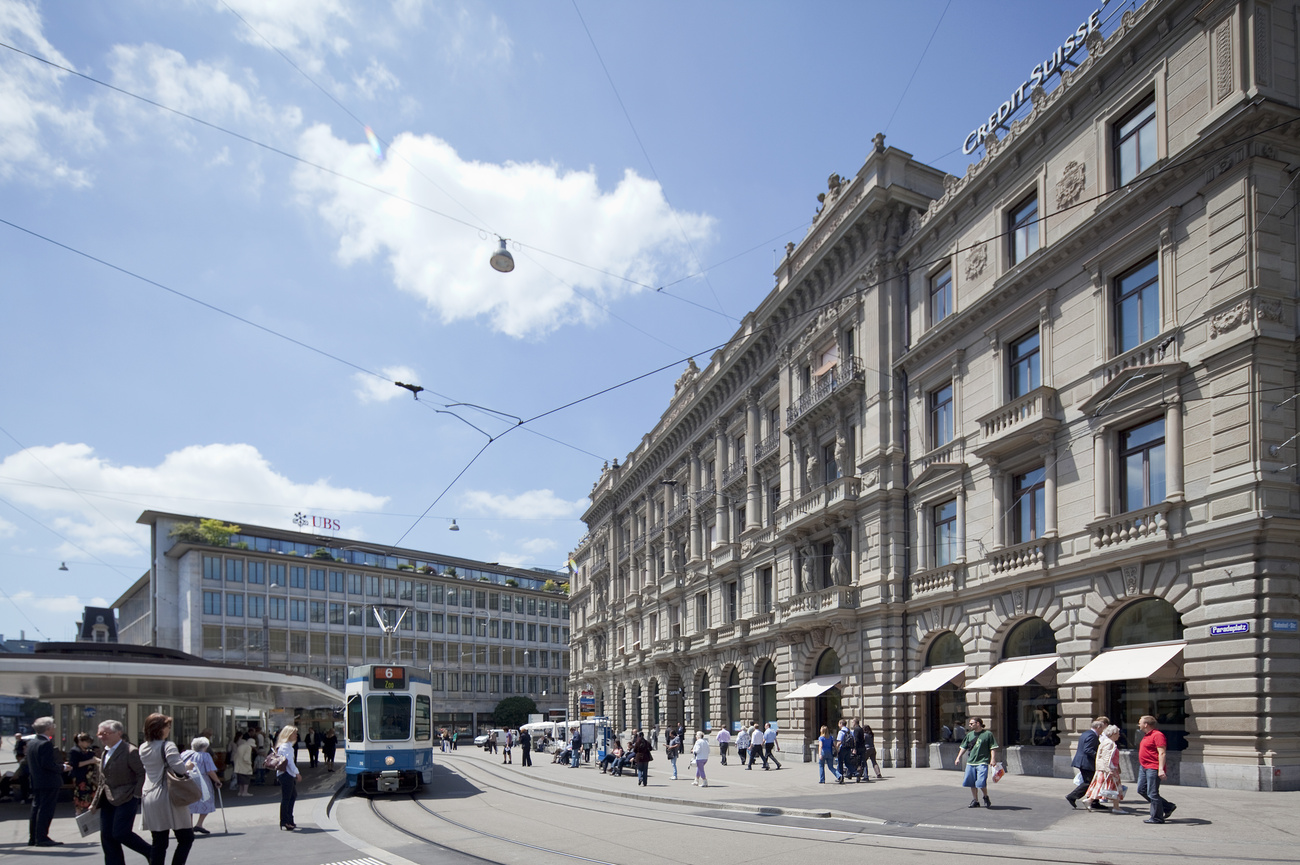 Passanten warten am 4. Juni 2010 auf dem Paradeplatz in Zürich auf das Tram. Im Hintergrund sind der Hauptsitz der UBS AG (Mitte) und jener der Credit Suisse (rechts) zu sehen.