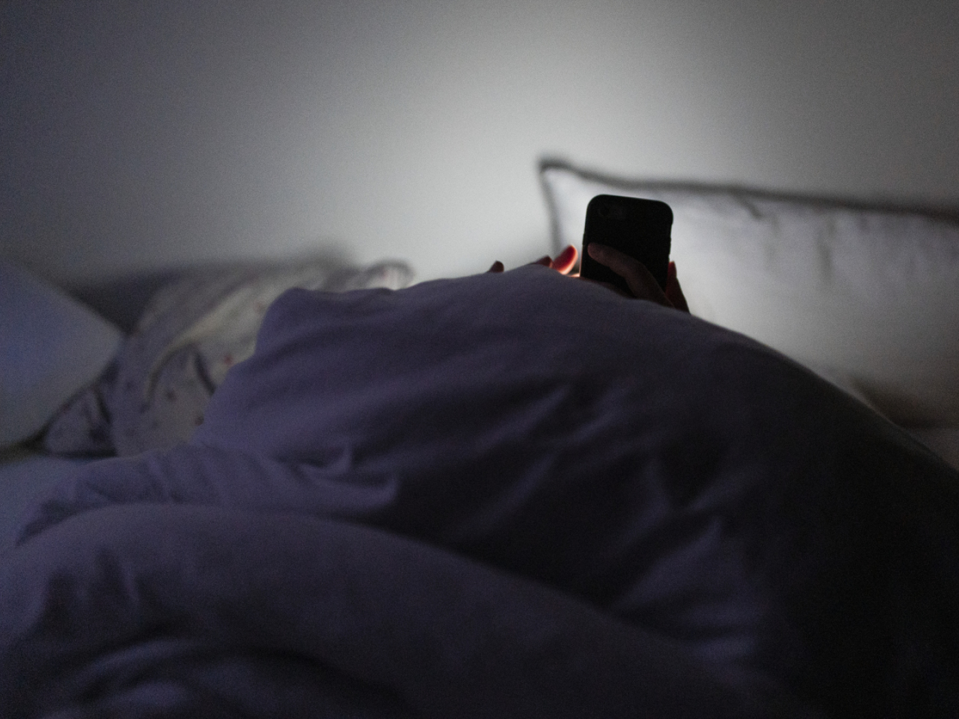 persona a letto scrolla sul telefono