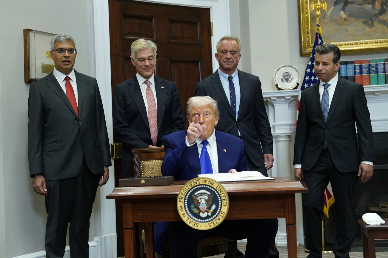 man at desk and four men standing behind him.