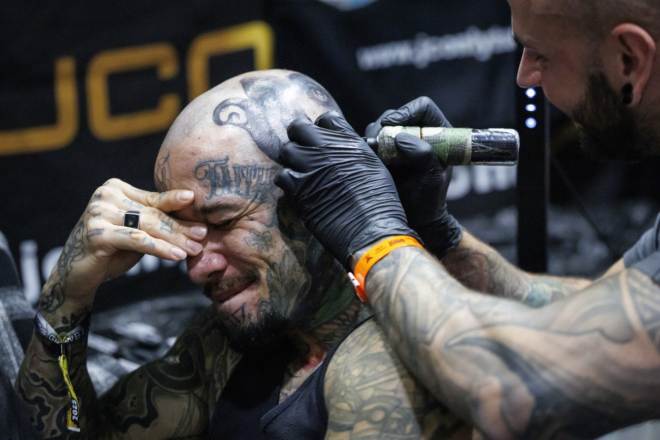 uomo si fa tatuare in testa, espressione del viso sofferente
