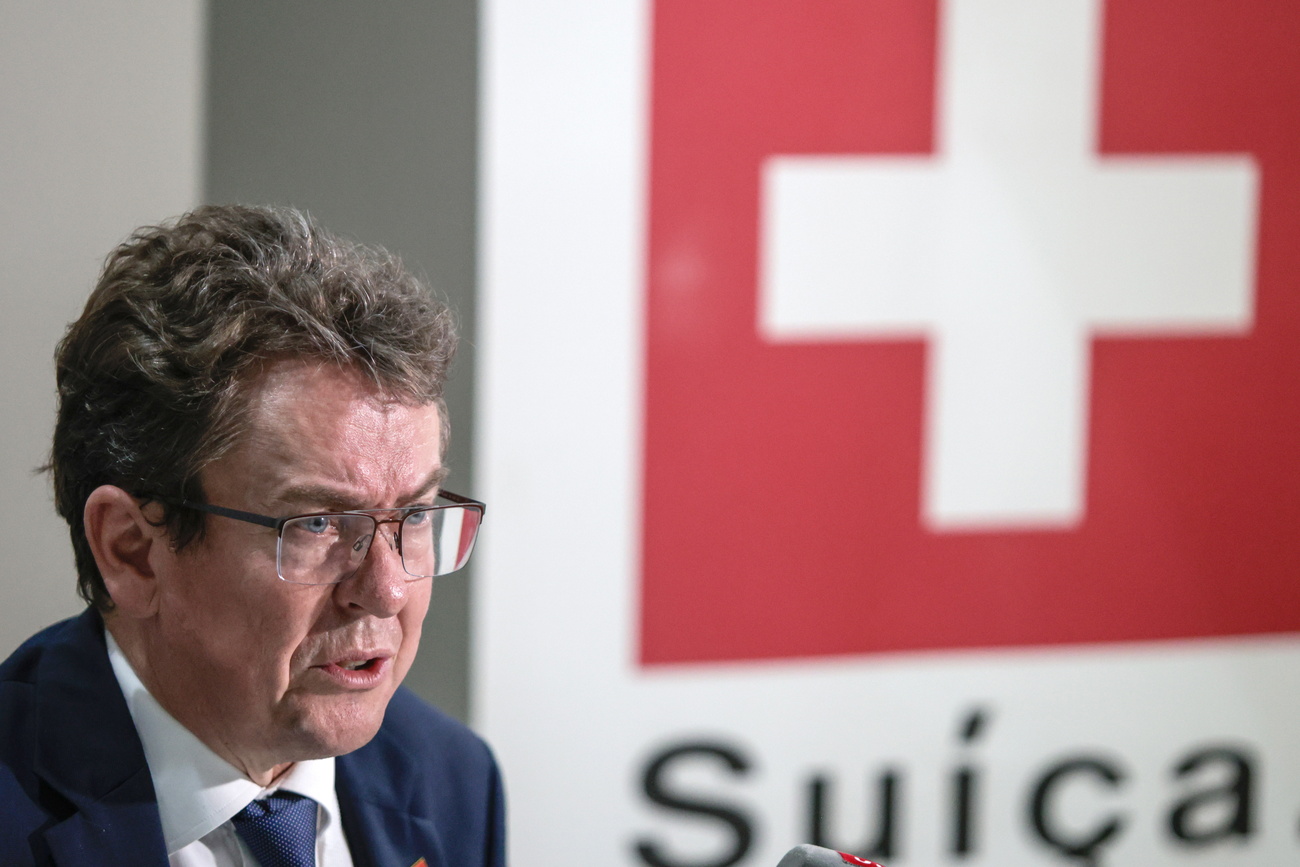 Um homem frente a uma bandeira da Suíça