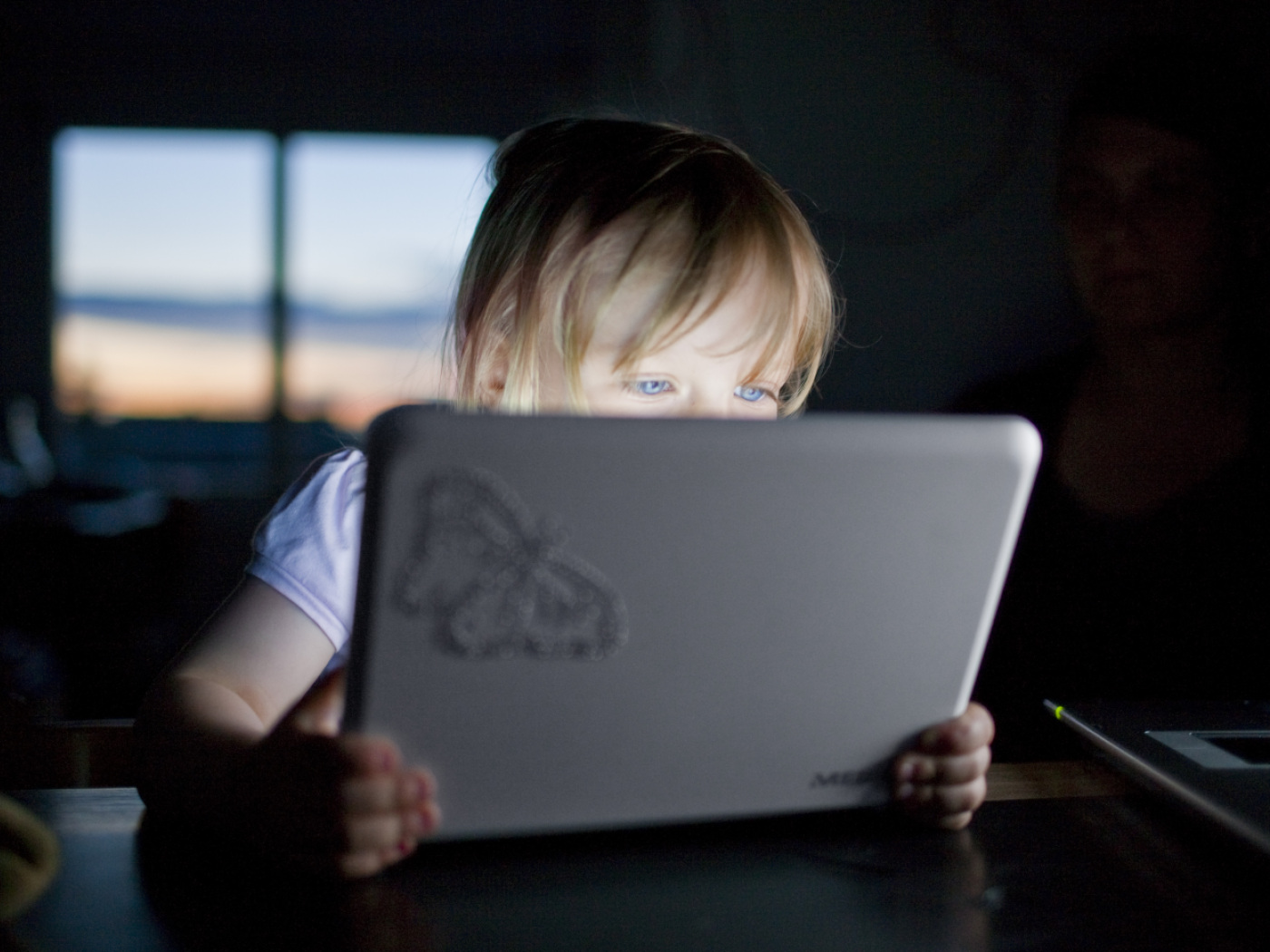 bambina guarda qualcosa su un tablet che le illumina il viso