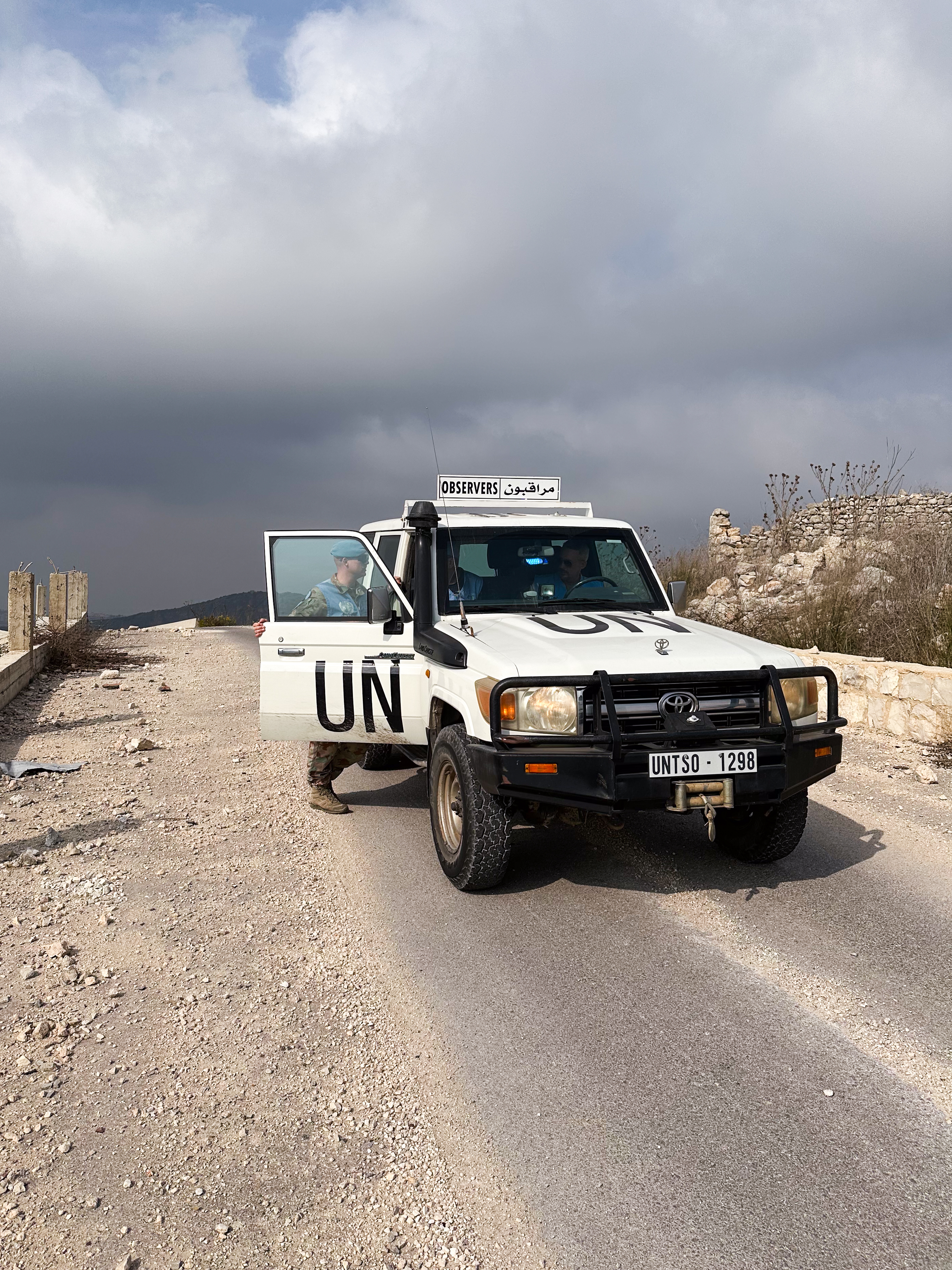 Ein UNTSO-Patrouillenfahrzeug steht auf einer Schotterstrasse, mit einem Soldaten an der offenen Tür