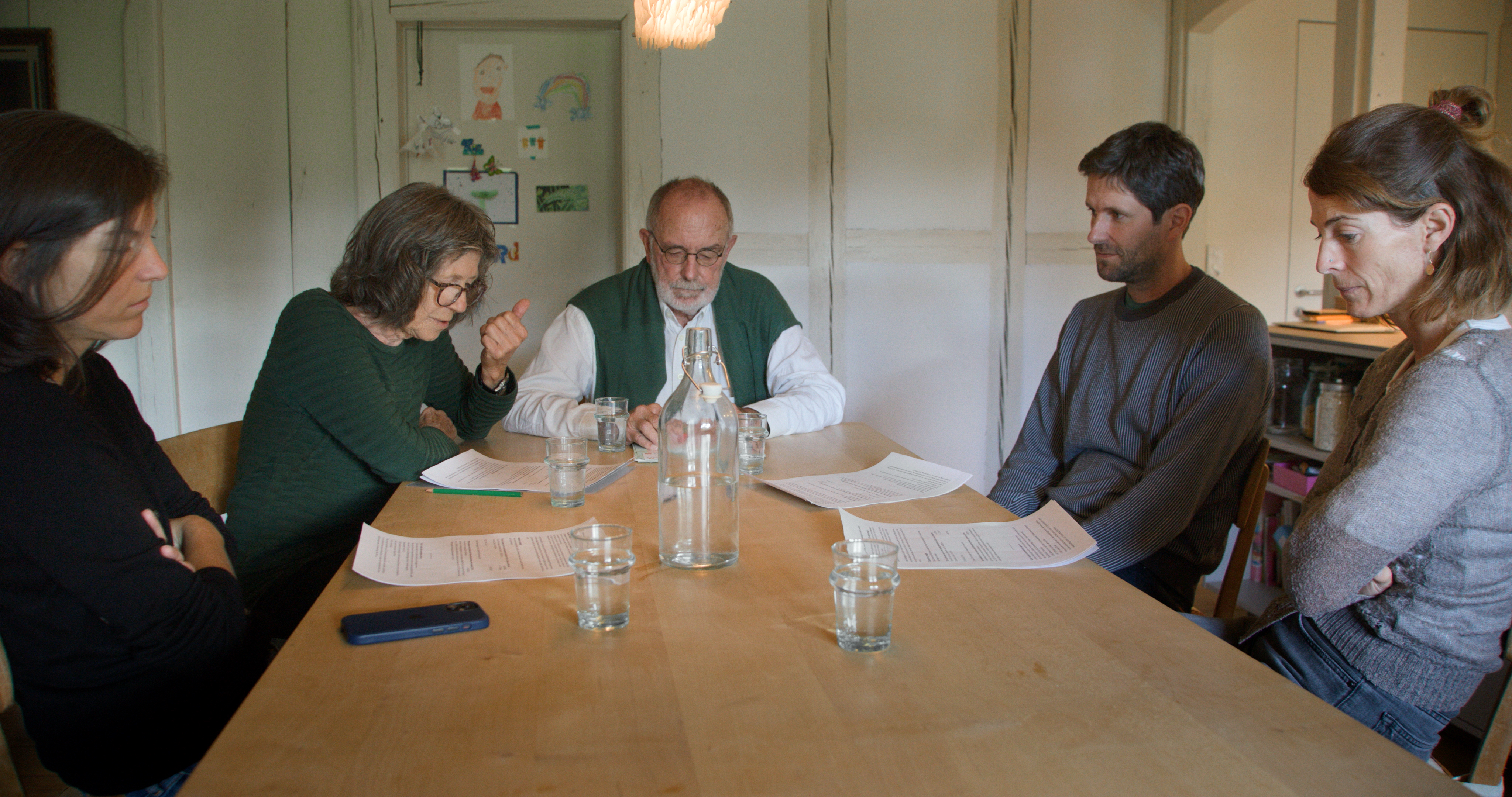 Eine Familie mit zwei Generationen von Erwachsenen sitzt an einem Tisch.