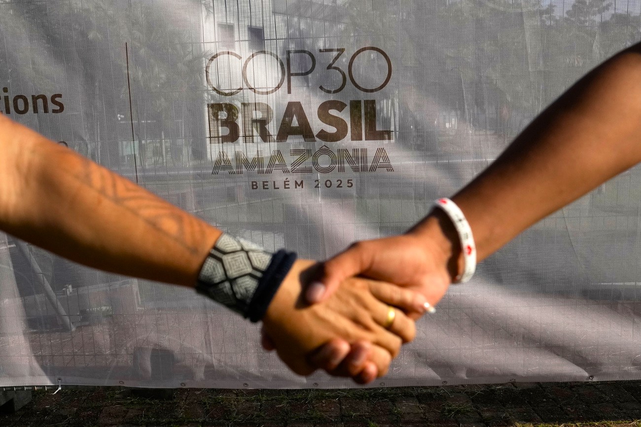 two hands hold in front of the cop30 sign