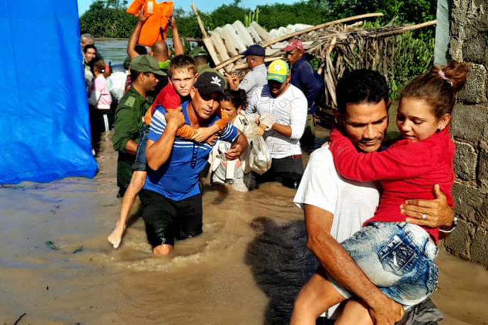 People walk through floods, children are carried
