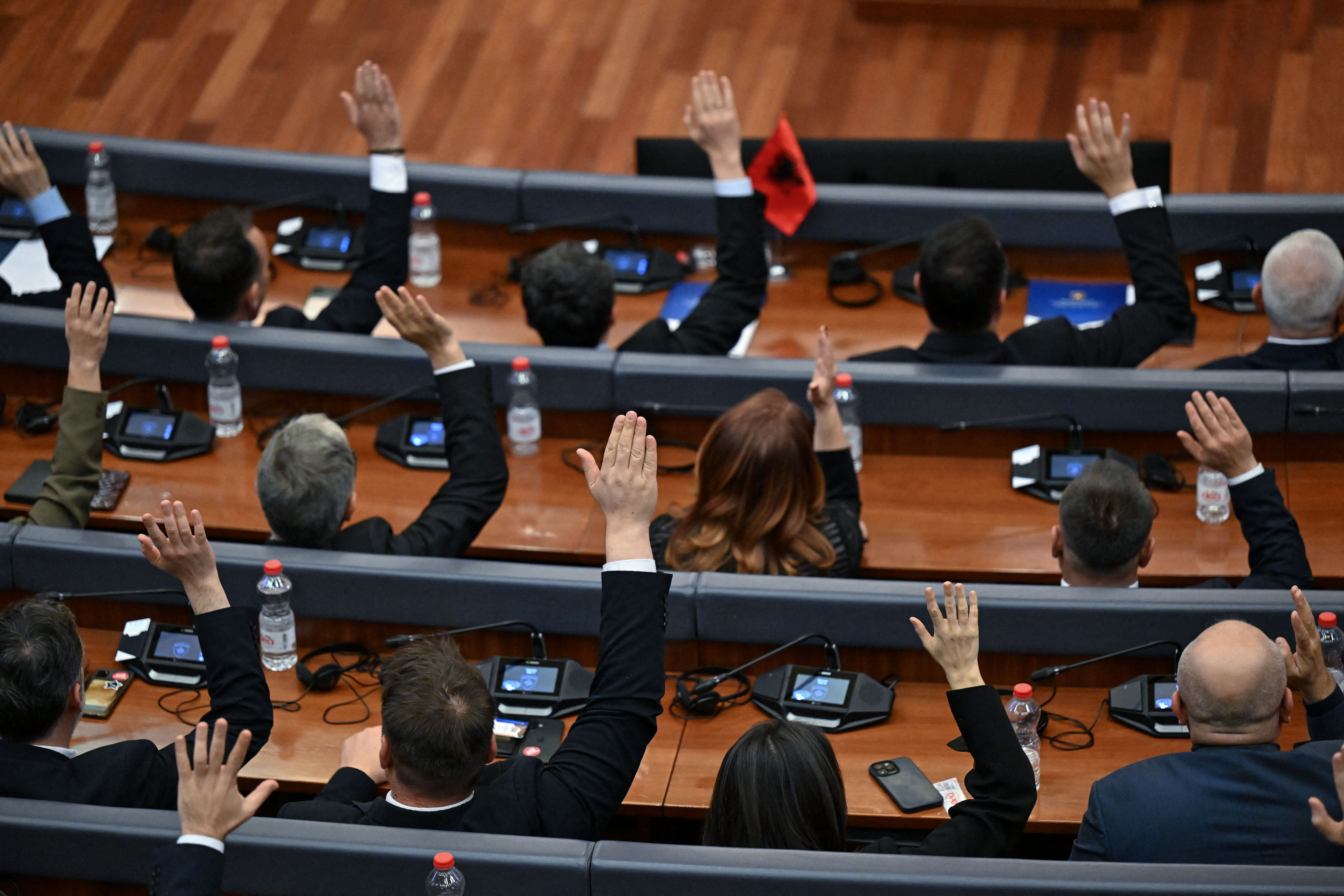 Eine Gruppe von Menschen hebt während einer Sitzung im Parlament die Hände