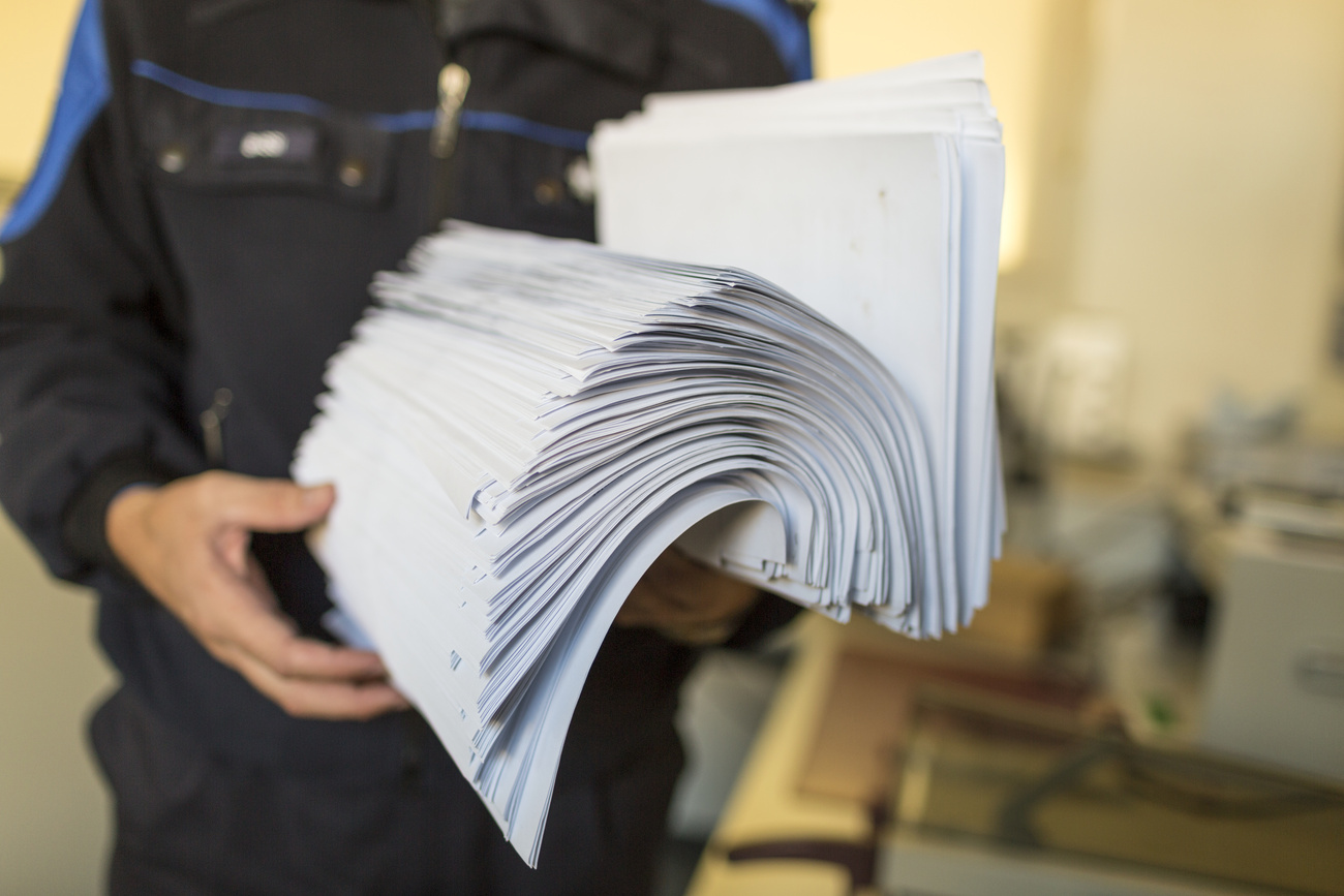 Una guardia di frontiera tiene in mano un pacco di formulari.