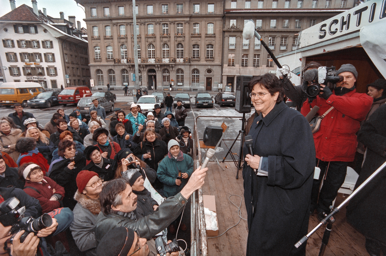 A woman in the stands, lots of fans and press people