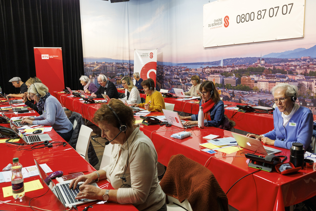 Zahlreiche Freiwillige sitzen an Laptops mit Headsets