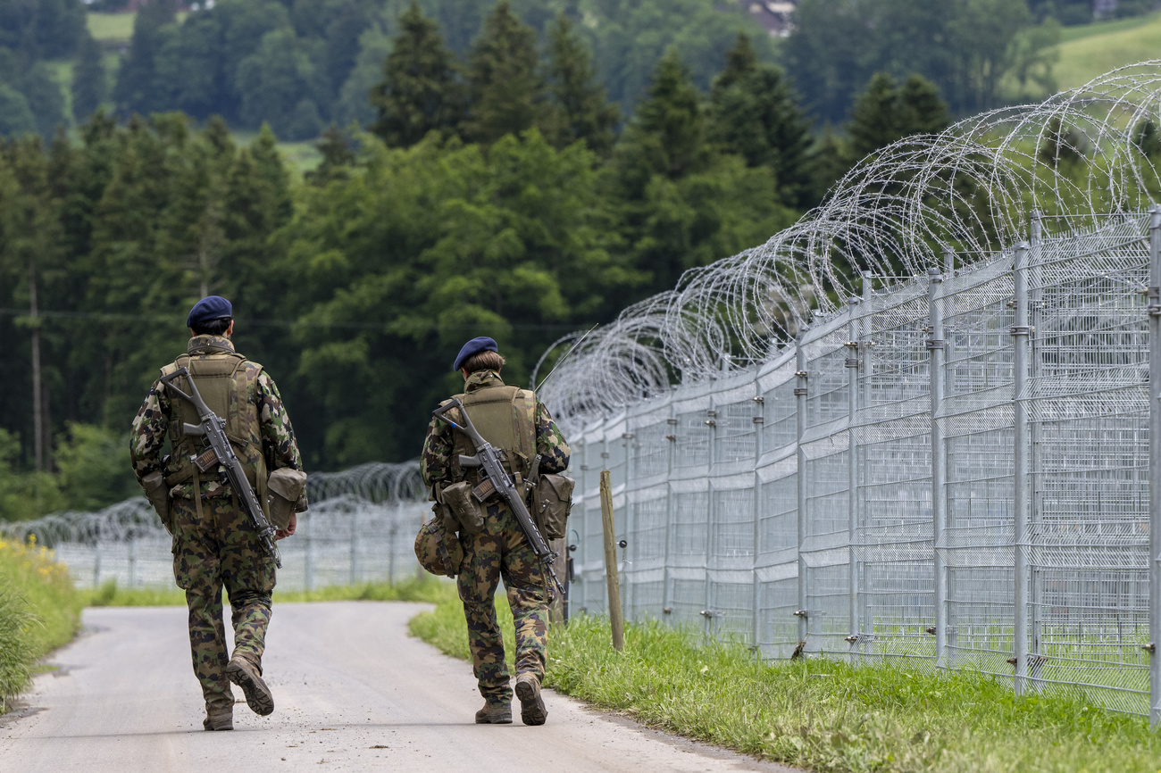 Due soldati di spalle accanto a una recinzione