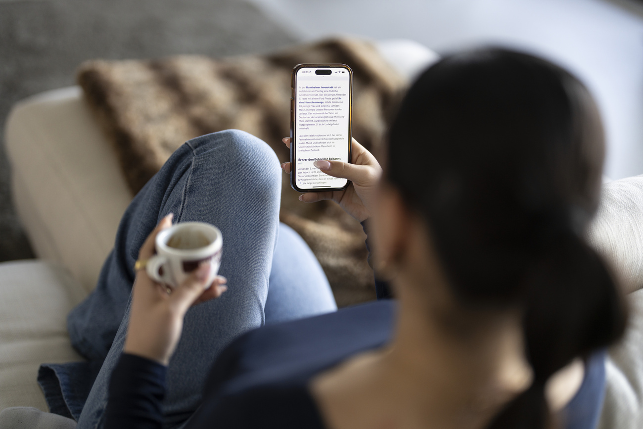 una donna guarda il suo cellulare mentre befe un caffé