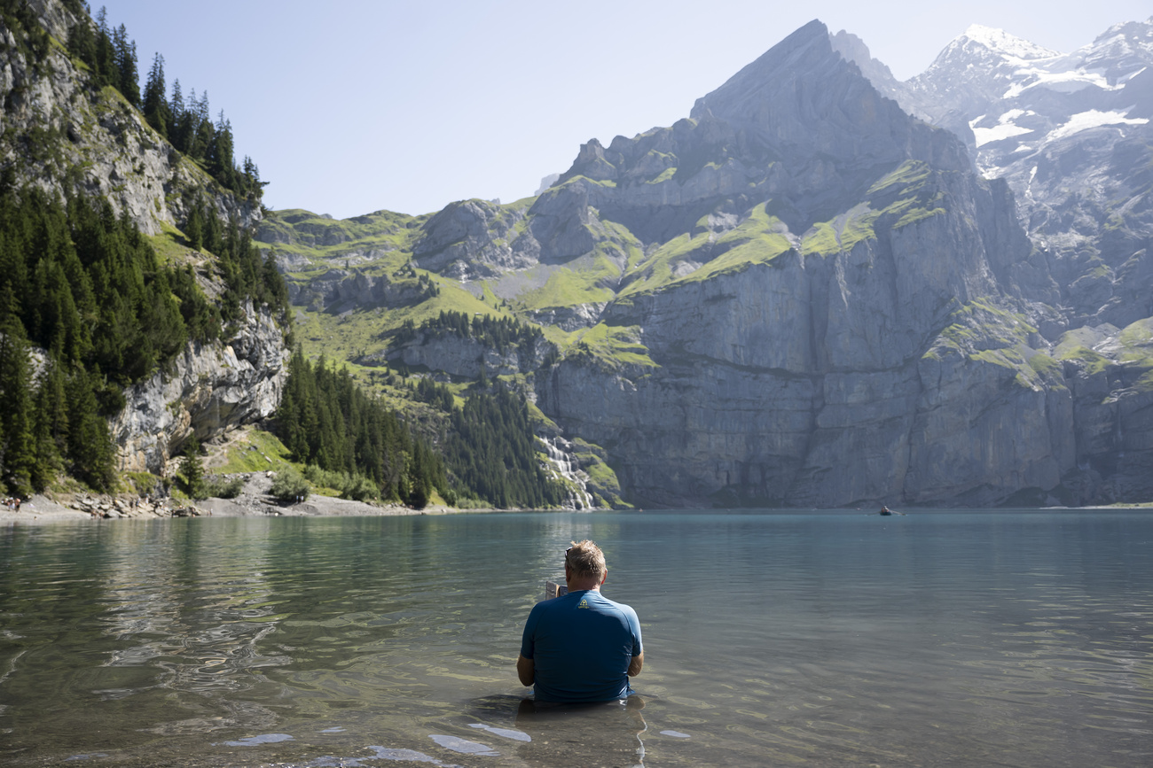 uomo seduto vestito nell'acqua di un laghetto alpino