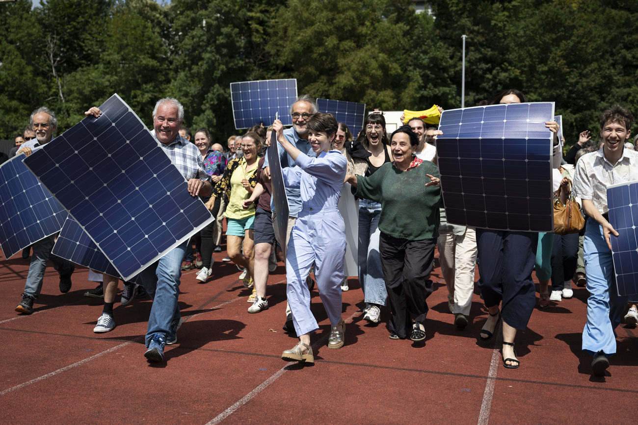 瑞士绿党主席丽莎-马佐内（Lisa Mazzone）与党员们一起举着代表太阳能电池板的牌子合影留念。这张照片是在他们一致通过题为 "不感谢核能！今天，太阳能发电势在必行！"的决议后拍摄的。