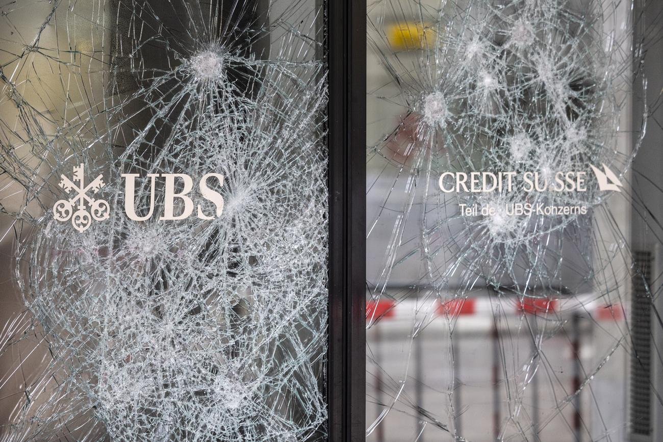 Eingeschlagene Fenster mit den Logos von UBS und Credit Suisse