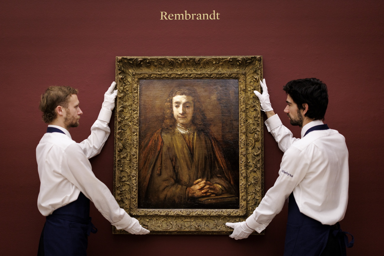Due uomini tengono in mano un quadro di Rembrandt.