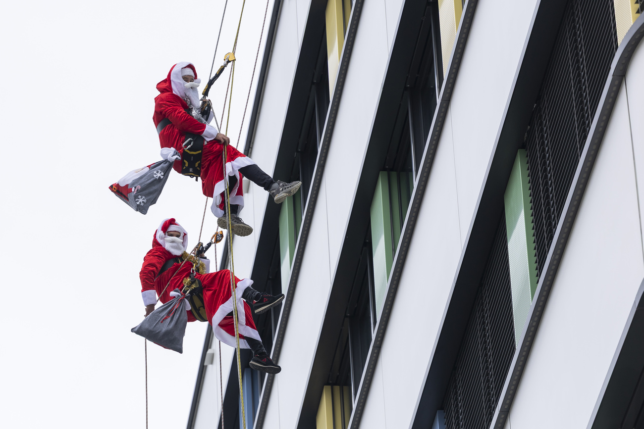 Due persone vestite da Babbo Natali si calano lungo una parete